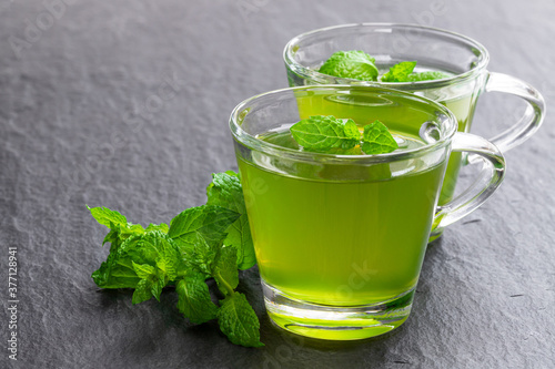 Cup of green tea with jasmine and mint on stone background