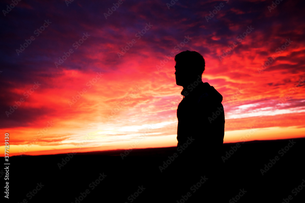silhouette of young man with colorful sky clouds, sunset time, 
