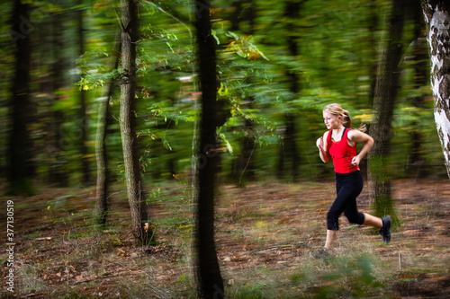 Pretty. young woman running fast in a forest - motion blur technique used to convey speed and movement