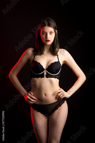 Cute brunette female model posing  wearing black underwear in dark studio