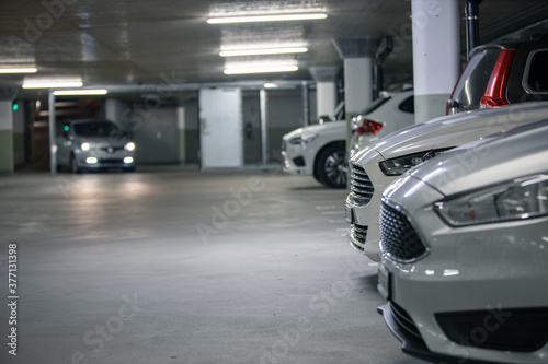 Underground parking. Cars parked in a garage with no people. Many cars in parking garage interior. Underground parking with cars (color toned image)