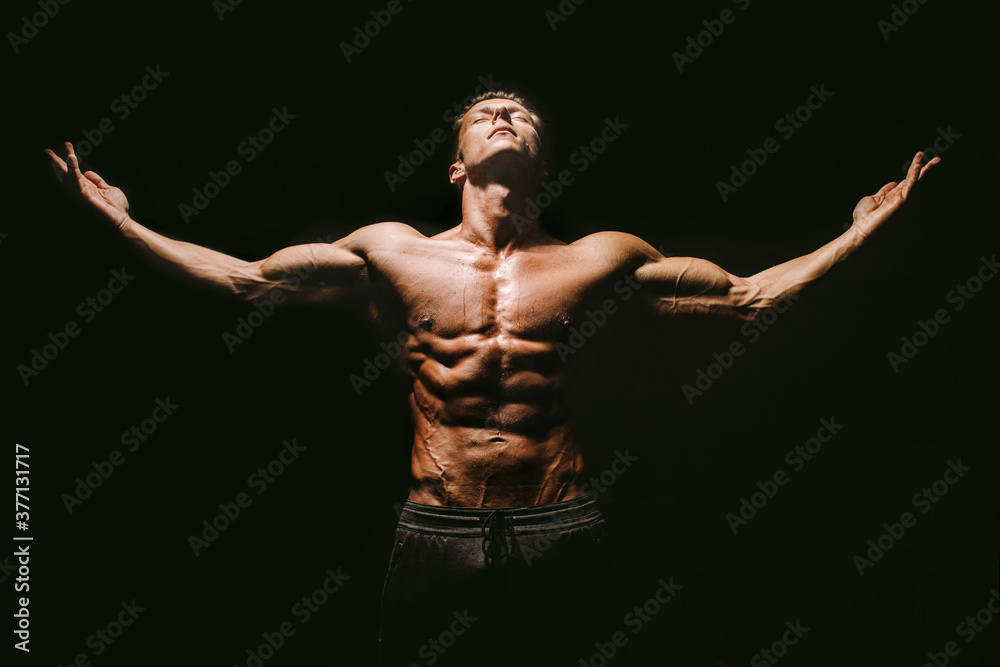 muscular body man posing on black background. Bodybuilder posing hands up. Attractive sporty guy wet and hot. Fitness model muscled man. Looking and Hands up. Calm and harmony muscular body man posing on black background. Bodybuilder posing hands up. Attractive sporty guy wet and hot. Fitness model muscled man. Looking and Hands up. Calm and harmony