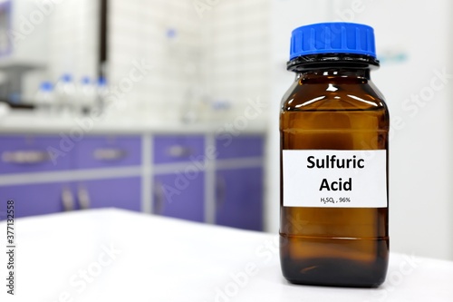 Selective focus of strong sulfuric acid chemical in brown amber glass bottle inside a laboratory with copy space. photo