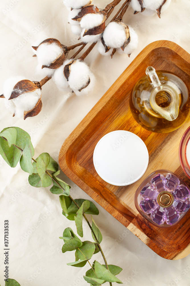 white cosmetic jar, perfume and eucalyptus scented oil on a wooden plate. spa-procedure. white cosmetic jar, perfume and eucalyptus scented oil on a wooden plate. spa-procedure.