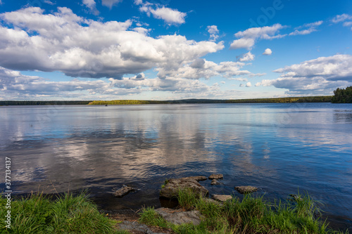 A picturesque landscape with a lake and beautiful clouds in the sky. Ural landscape of nature.