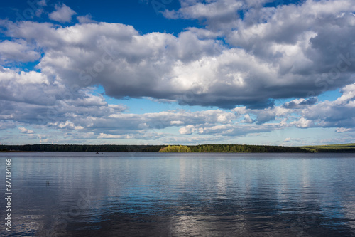 A picturesque landscape with a lake and beautiful clouds in the sky. Ural landscape of nature.
