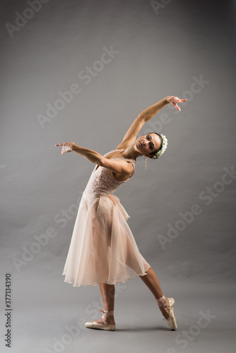 Fototapeta Naklejka Na Ścianę i Meble -  Beautiful ballet dancer posing on pointes on light grey studio background