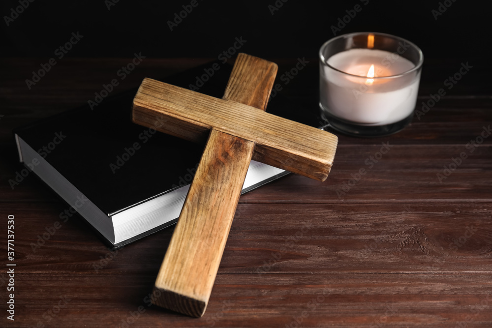 Obraz premium Cross, Bible and burning candle on wooden background, closeup. Christian religion