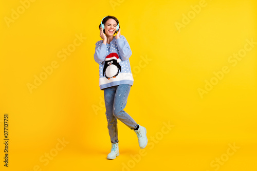 Full body photo of attractive lady youth student party newyear listen cool modern technology earphones radio wear ugly ornament sweater pullover jeans boots isolated yellow color background © deagreez