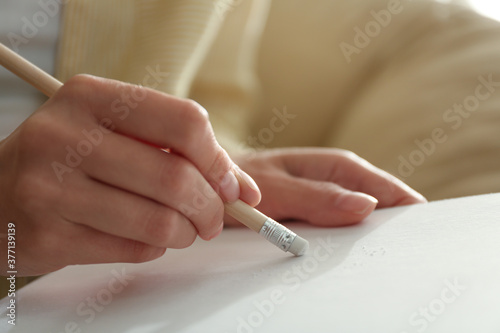 Woman correcting picture on paper with pencil eraser, closeup