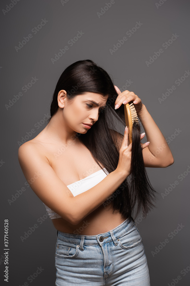 sad brunette woman brushing hair isolated on black sad brunette woman brushing hair isolated on black