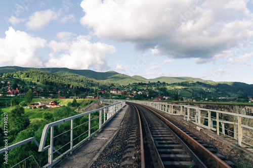 Railway track on the bridge on the background of a beautiful mountain landscape. Suburban railway on the background of the village and mountains. Vorokhta. Ukraine, Carpathians