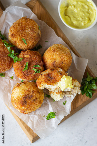 Classic homemade Italian arancini. Fried rice balls with minced meat served with parsley and cheese sauce. Top view.