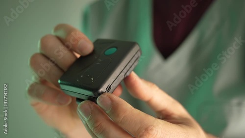 80s 90s vintage pager beeper being used by a doctor or nurse wearing a uniform. The pager is still used today in many medical facilities. photo