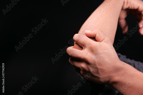 man with elbow pain isolated in black. Pain relief concept.