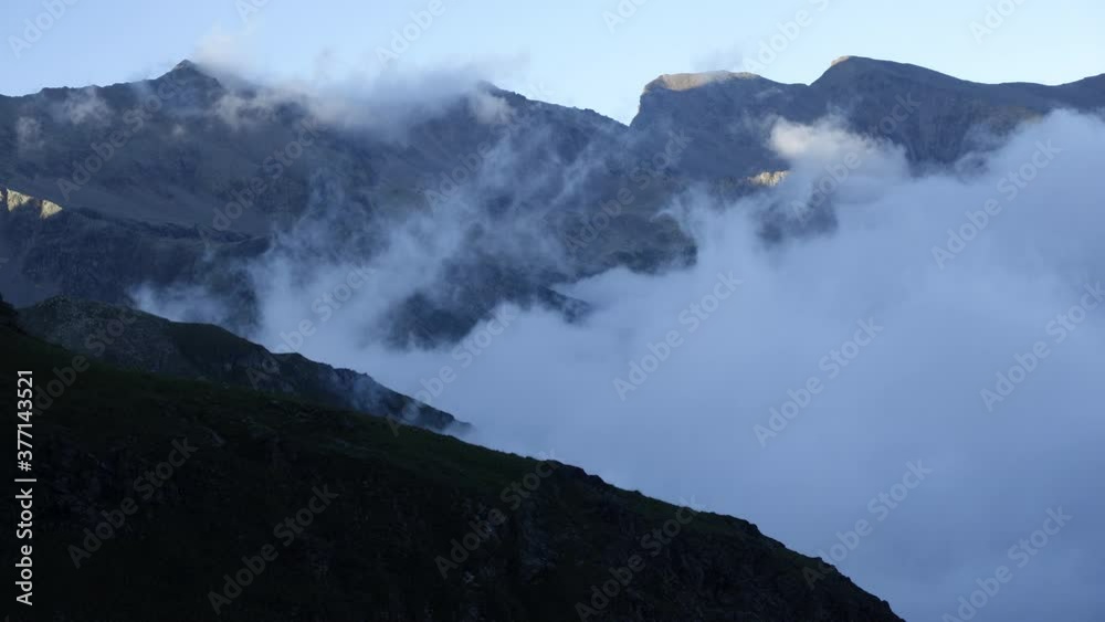 Clouds in a mountain valley. Beautiful waves of clouds flowing in the mountains. The last rays of the sun on the tops of the mountains in the clouds at sunset. Time-laps.
Clouds in a mountain valley. Beautiful waves of clouds flowing in the mountains. The last rays of the sun on the tops of the mountains in the clouds at sunset. Time-laps.