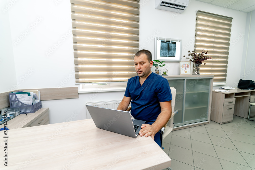 Man doctor giving video chat to the client on laptop at hospital. Pandemic restrictions. Man doctor giving video chat to the client on laptop at hospital. Pandemic restrictions.