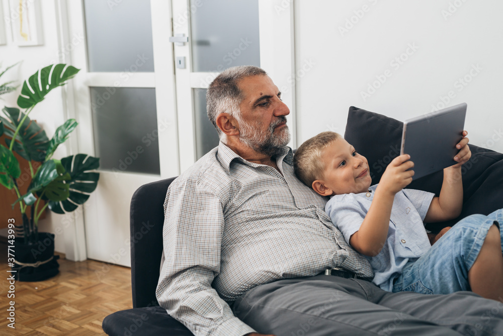 grandson with his grandfather using laptop computer at home grandson with his grandfather using laptop computer at home
