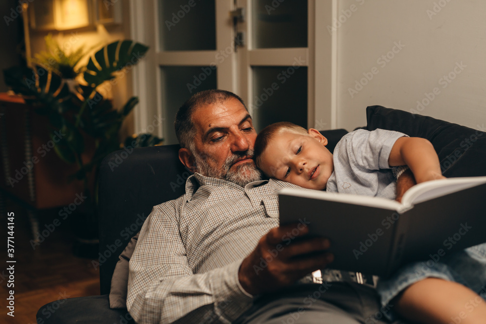 grandson with his grandfather enjoying time together reading book at home grandson with his grandfather enjoying time together reading book at home