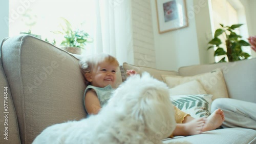 Portrait of young baby girl laughing on a sofa at home.