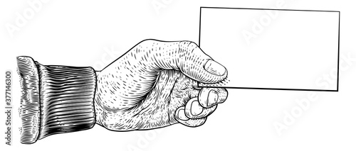 A hand holding a business card, letter, message, flyer or similar with copyspace in a vintage engraved or etched woodcut print style
