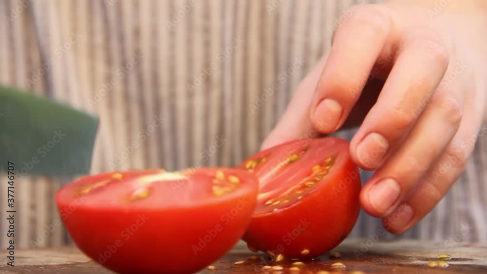 Slicing tomato close up. The girl cuts the tomatoes. Tomatoes and a knife. Cooking food. Preparation of ingredients Slicing tomato close up. The girl cuts the tomatoes. Tomatoes and a knife. Cooking food. Preparation of ingredients