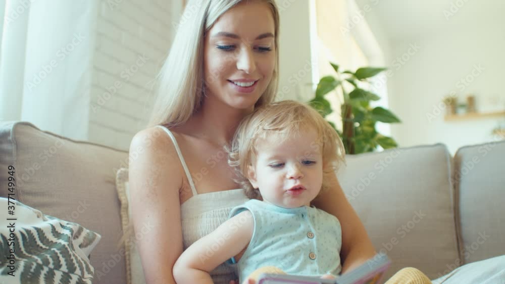 Young beautiful mother playing with baby daughter on sofa at home. Young beautiful mother playing with baby daughter on sofa at home.