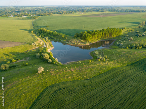 Aerial drone view. Country lake. Green grass on the shore. © Sergey
