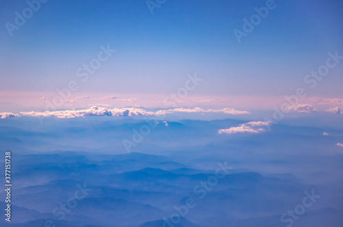 Atmospheric and beautiful soft photos from the airplane window  mountains on the horizon and beautiful volumetric landscapes  pink tint