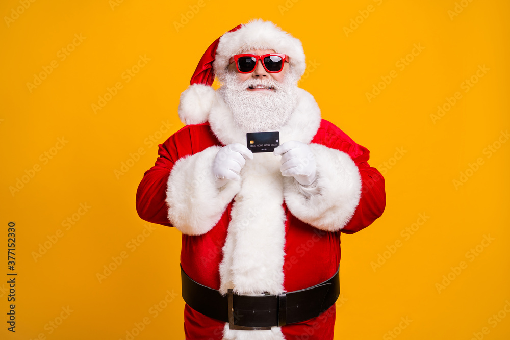Portrait of his he nice attractive cheerful cheery Santa holding in hand bank card spend budget safe shopping isolated bright vivid shine vibrant yellow color background Portrait of his he nice attractive cheerful cheery Santa holding in hand bank card spend budget safe shopping isolated bright vivid shine vibrant yellow color background