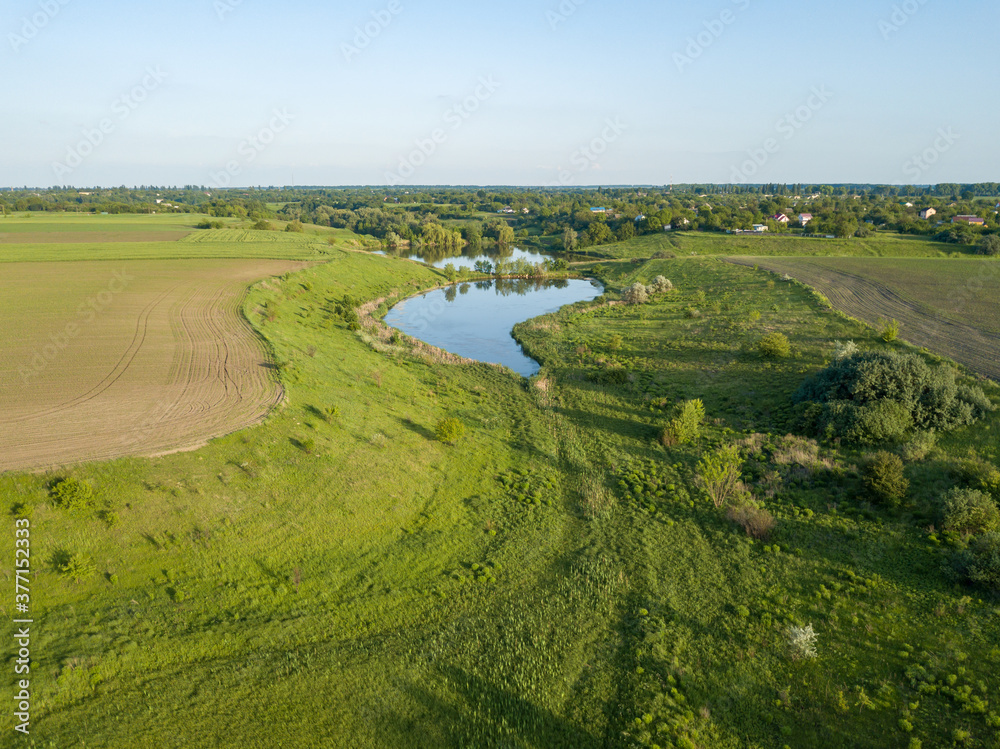 Lake among agricultural fields. Aerial drone view.