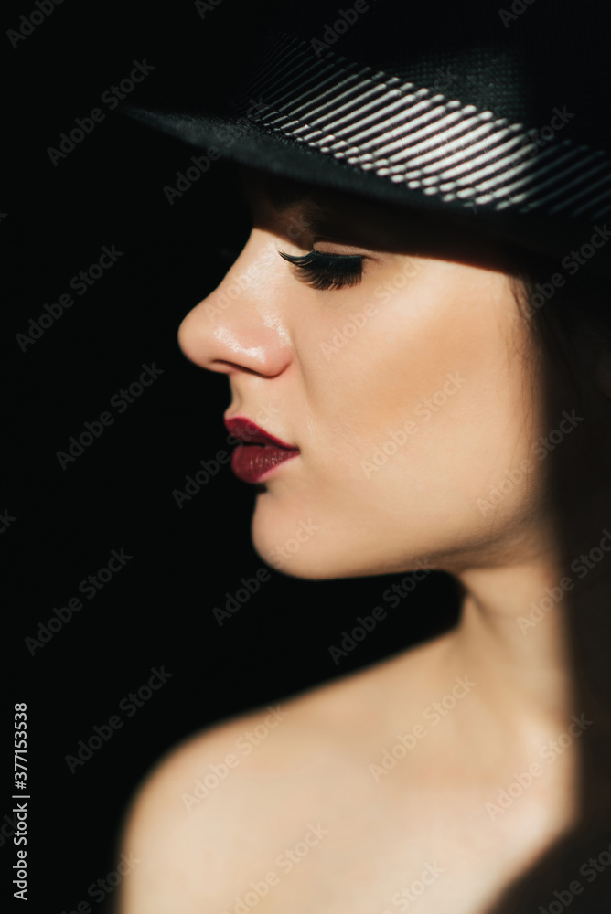 fashion portrait in profile of a young sexy girl in a black hat with red lipstick fashion portrait in profile of a young sexy girl in a black hat with red lipstick