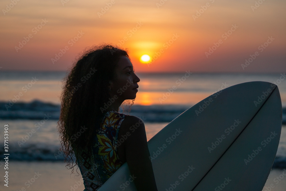 Portrait of woman surfer with beautiful body on the beach with surfboard at colorful sunset Portrait of woman surfer with beautiful body on the beach with surfboard at colorful sunset