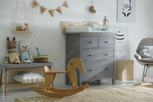 Beautiful baby room interior with toys and modern changing table