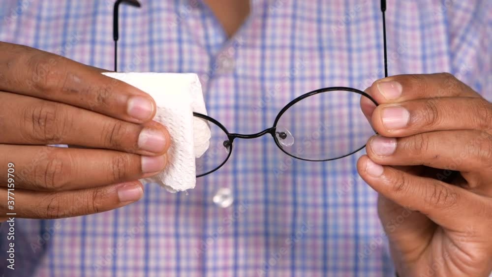 Close up of man hand cleaning eyeglass with tissue Close up of man hand cleaning eyeglass with tissue
