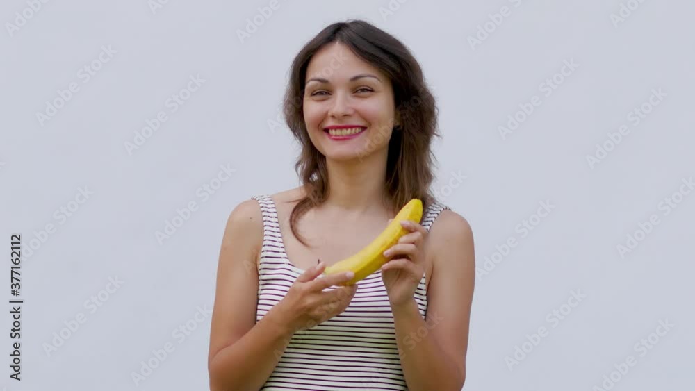 young attractive woman on a white background holding a banana. woman eating banana on white background young attractive woman on a white background holding a banana. woman eating banana on white background