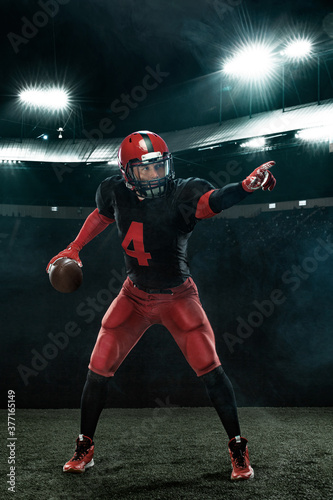 American football player in action, athlete sportsman in red helmet on stadium background. Sport and motivation wallpaper.