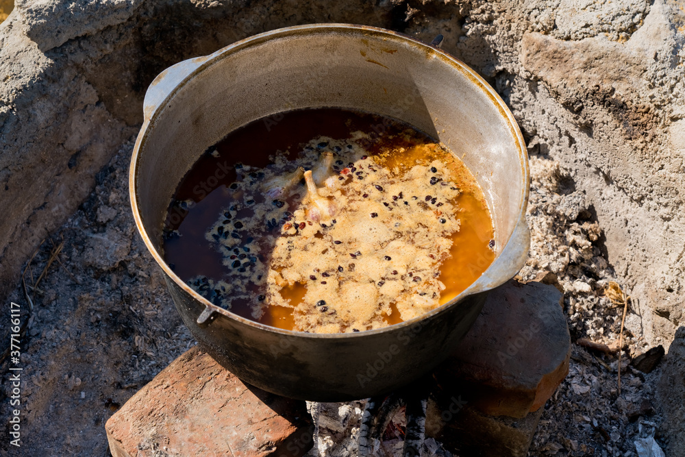 Cooking pilaf in a large cauldron over an open fire. Close-up. Cooking pilaf in a large cauldron over an open fire. Close-up.