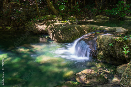 Fototapeta Naklejka Na Ścianę i Meble -  Clear stream that flows through the rocks. Falling into the Emerald Pool, Erawan Kanchanaburi, Thailand.
