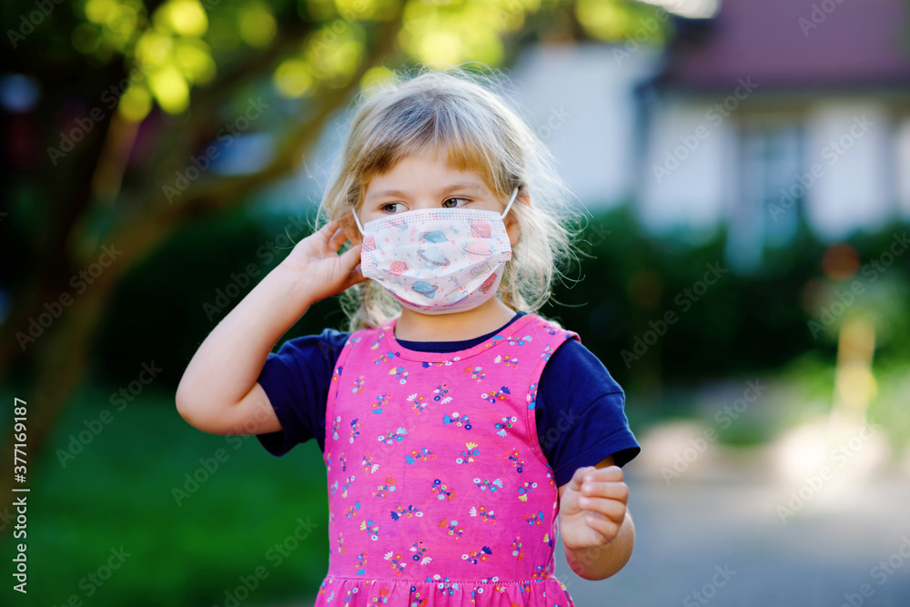 Little toddler girl in medical mask as protection against pandemic coronavirus quarantine disease. Cute child use and put protective equipment as fight against covid 19. Little toddler girl in medical mask as protection against pandemic coronavirus quarantine disease. Cute child use and put protective equipment as fight against covid 19.
