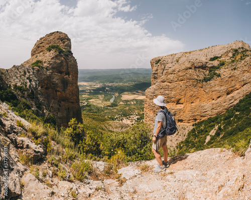 A young athletic woman stops at viewpoint along the Riglos rock track. photo