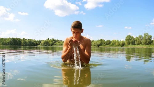 Young naked man washing his face with water on the lake