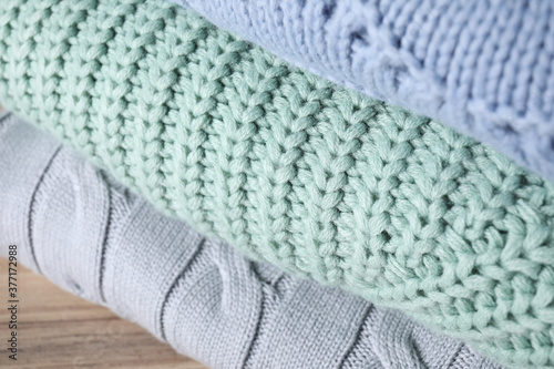 Stack of folded warm sweaters on wooden table, closeup