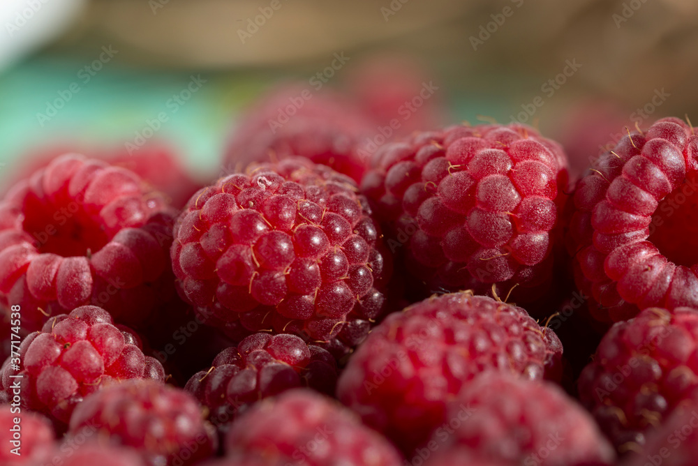 Juicy red raspberries lie in a pile on a blurry background Juicy red raspberries lie in a pile on a blurry background