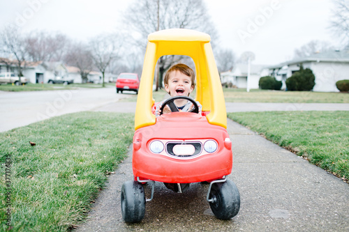 little boy riding in red toy car