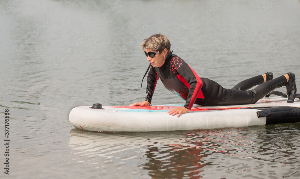 Obraz premium active woman 65 years in wetsuit swimming on surf 