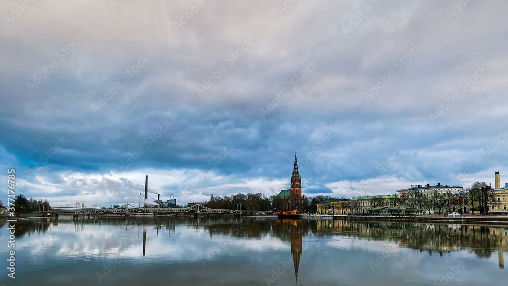The view of Pori city reflected in Kokemäenjoki River with the The Central Pori Church and working sawmill (with high chimney from which smoke comes out). Pori - city on the west coast of Finland