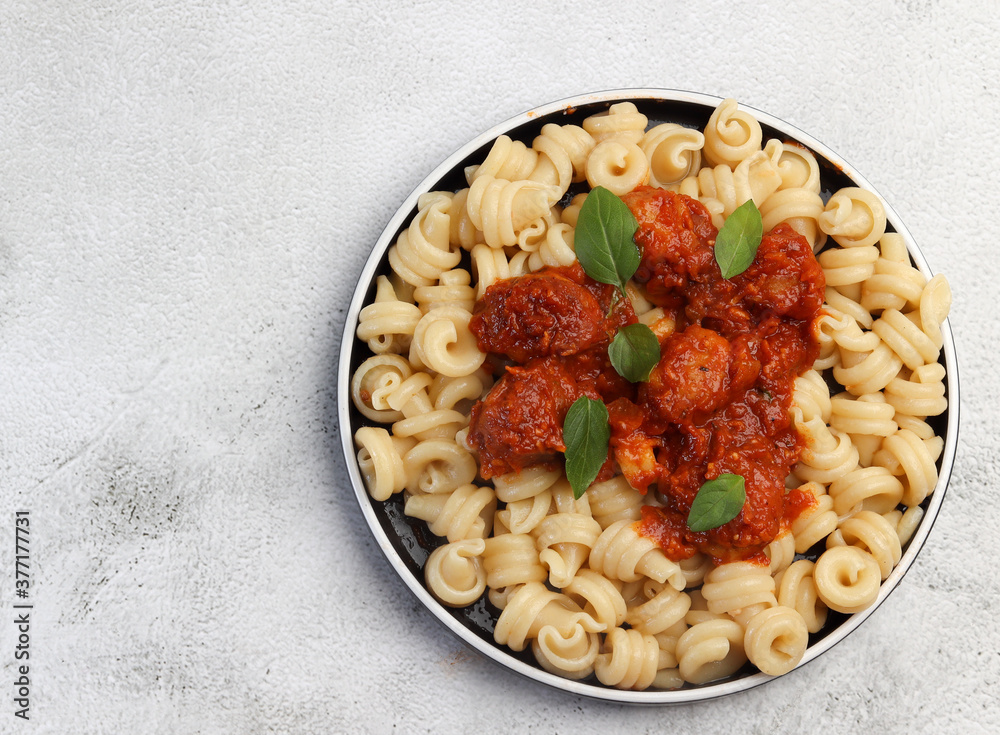 Pasta with meatballs in tomato sauce on a round plate on a light gray background. Top view, flat lay Pasta with meatballs in tomato sauce on a round plate on a light gray background. Top view, flat lay