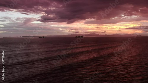 Beautiful cinematic aerial view of a great sunset in the middle of the ocean with a huge cruise ship and palm trees photo