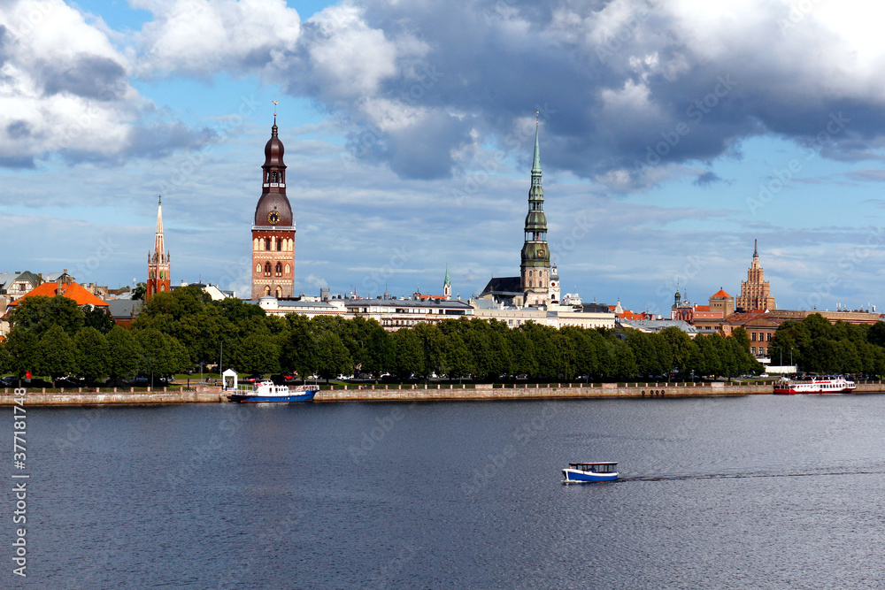 Beautiful panoramic view of the old town of Riga, Latvia. Amazing cityscape with clouds and a boat floating on the river.